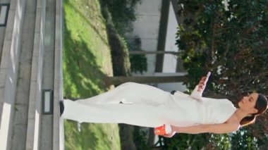 Merdivenlerden inen dikey iş kadını. Güneşli bir sokakta telefon arıyor. Kahve fincanı ile akıllı telefon ekranı okuma mesajına odaklanmış zarif bir kadın. Zengin kadın elinde telefonla aşağıya iniyor.