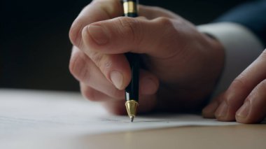 İş adamı elleri çalışma masasındaki resmi belgeye imza atıyor. Bilinmeyen yönetmen sözleşme sözleşmesi beyannamesi imzalıyor. İşadamı şirket belgelerini onaylıyor.