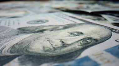 Closeup image Benjamin Franklin on hundred us dollar banknote rotating. Large heap of 100 usd new type with portrait american president lying on surface. Pile money cash usa currency bills background.