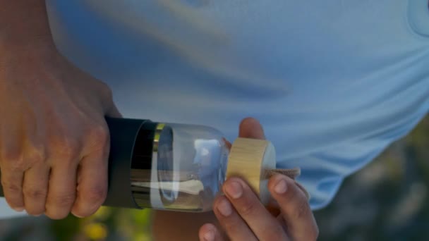 运动员在海崖特写处喝瓶装水 适合男人在海上晨练后打开酒壶解渴 — 图库视频影像