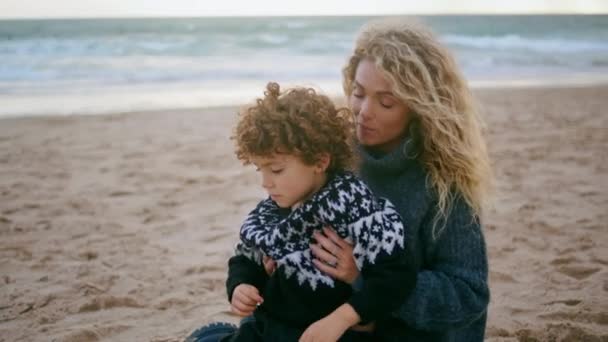 妈妈盖着毛毯孩子在寒冷的海滩野餐特写 无条件的父母之爱可爱的卷曲的儿子享受友好的谈话拥抱与美丽亲切的妈妈保姆 爱母爱关系 — 图库视频影像