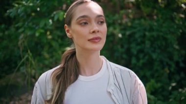 Yeşil orman yaz gününde poz veren nazik kadın portresi. Çekici, dingin, güzel yeşil parkta oturan kameraman kız. Güneşli doğada gevşeyen muhteşem genç manken. Yaklaş..