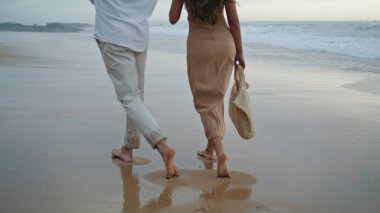 Couple legs crossing ocean at summer closeup. Affectionate spouses enjoying seashore. Positive newlyweds feeling happy spending honeymoon together. People rest at foggy coast. Vacation concept 