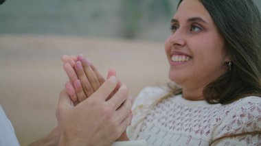 Laughing woman bonding man at beach closeup. Unknown boyfriend warming lady arms at cold summer evening. Loving couple relaxing at dark nature. Ethnic lovers touching hands at anniversary vacation