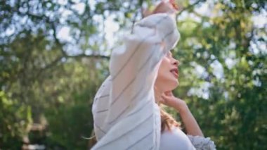 Modern kablosuz kulaklıkla müzik dinleyen yürüyen bir kadın. Tasasız kız Green Park 'ta en sevdiği şarkı boyunca el kaldırıyor. Huzurlu bayan ormanda kulaklık seslerini sever.