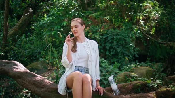 Romantická Dívka Čenichající Květina Sedí Zeleném Lese Ležícím Kmeni Stromu — Stock video