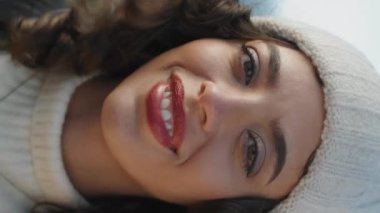 Rüzgarlı bir günde, dikey çekim yapan neşeli kız. Mutlu genç gezginler okyanus kıyısında dinleniyor bahar tatilinin tadını çıkarın. Gülen kadın turist örgü şapkayla mutlu görünüyor. Açık hava gezisi eğlencesi.