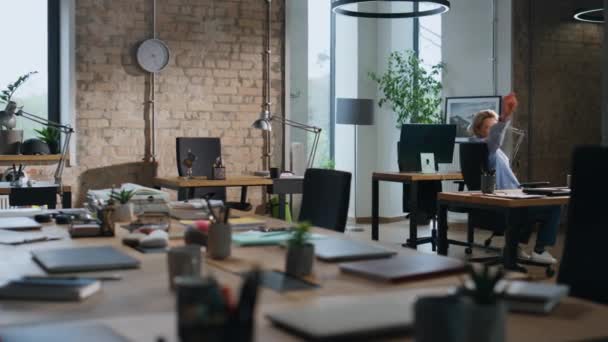 办公室职员在空荡荡的现代化办公室里坐在桌子中间 在工作后独自在工作空间里玩乐的轻松的女人 女商人在工作日休息 人力资源概念 — 图库视频影像