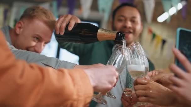 生日宴会上 朋友们在玻璃杯里斟酒 笑得很开心 愉快的商人们喝着香槟酒庆祝在位期间的商业成功 多种族团队在智能手机上记录庆祝活动 — 图库视频影像