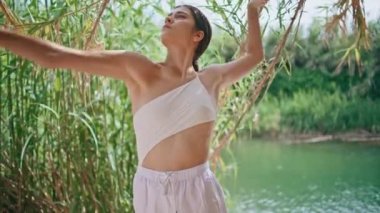 Esnek dansçı yaz doğasında zayıf seksi vücudu eğiyor. Yaklaş. Şehvetli kadın turkuaz gölde çağdaş dans gösterisi yapıyor. Genç model duygusal koreografi pratiği yapıyor.