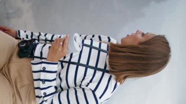 Seyahat eden kız deniz kenarında dikey kahve içiyor. Akdeniz mimarisine hayran olan güzel bir turist. Gülümseyen fotoğrafçı içecek yaz tatilini rahatlatır. Huzurlu bir hafta sonu gezisi