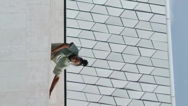 階段の垂直ビデオで振付を練習する柔軟な男 アフリカ系アメリカ人が都市ビルでダンスパフォーマンスをしている 抽象的な壁の背景でフリースタイルを踊るパフォーマー アート モダン — ストック動画