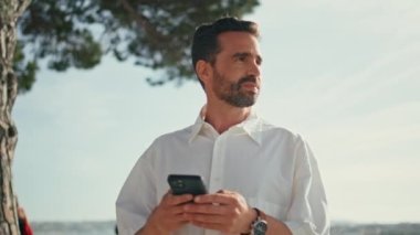 Şehir caddesinde gezen rahat turistler akıllı telefonları yakın çekimde tutuyor. Kaygısız yetişkin adam cep telefonu okuma mesajı kullanıyor. Akdeniz 'i gezen yakışıklı gezgin. Tatilin tadını çıkarıyor.