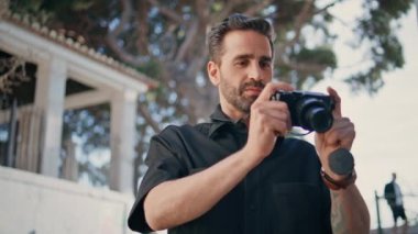 Turist, profesyonel kamera önünde fotoğraf çekiyor. Gülümseyen gezgin yaz gezisinin tadını çıkarıyor şehri keşfediyor. Tasasız adam tatil resimlerini tek başına yürütür. İtalyan fotoğrafçı çalışıyor.