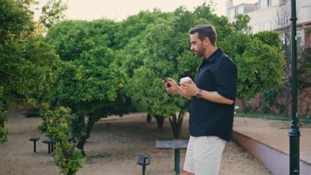 Sıradan Bir Adamı Cep Telefonuyla Şehir Bahçesinde Geziniyor Elinde Kağıt — Stok video