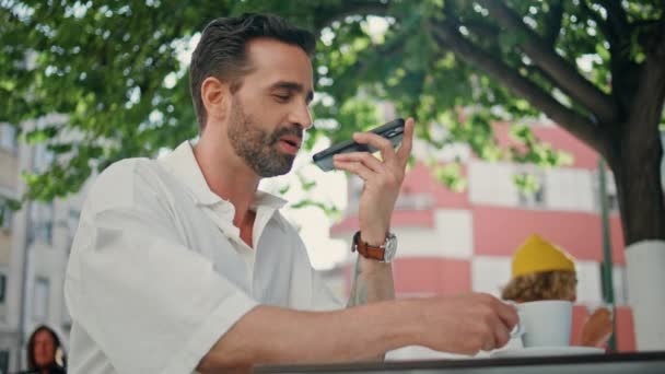 拉丁男人在街上的特写镜头里记录着喝咖啡的声音信息 英俊的自由职业者在户外用手机发送音频通知 有胡子的经理口述助教申请 — 图库视频影像