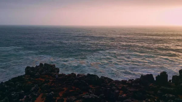 画龙点睛的空中海洋日出与深黑暗的波纹水面 在早晨的阳光下 泡沫浪以超慢的速度冲刷着粗糙的石质海岸线 金色的太阳升起在汹涌美丽的海面上 — 图库照片