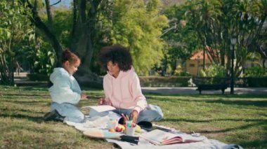 Aile piknik battaniyesinde güneşli yeşil doğada birlikte eğleniyor. Şirin Afro-Amerikan çocuğu mutlu kıvırcık annesiyle kağıda resim çiziyor. Rahat küçük kız çayır çimlerinde yaratıcılığın tadını çıkarıyor..