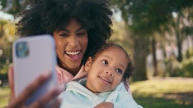 Anne, aile pikniğinde çocukla birlikte gülerken selfie çekiyor. Mutlu gülümseyen Afro-Amerikan kadın. Güneşli doğada telefonla fotoğraf çekiyor. Neşeli kızlar eğleniyor.