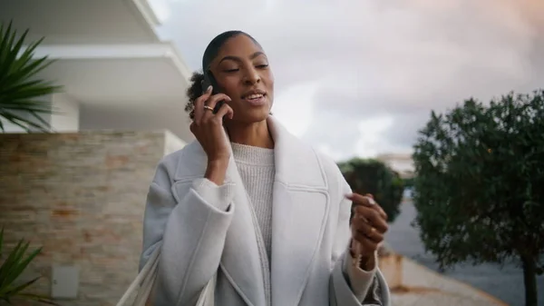 Attractive african american talking phone on street. Wealthy rich woman walking city hold key in hand. Stylish smiling businesswoman consult client partner after work. Successful real estate manager.