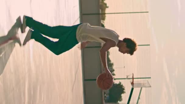 涉及青少年弹跳球在体育场 篮球运动员在城市操场上投篮筐 卷曲的年轻人正在垂直地训练宫廷 夏天早上打网球的那个人 体育活动 — 图库视频影像