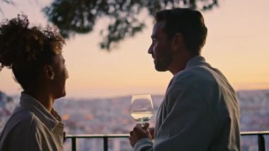 Aşıkların siluetleri gün batımında terasa bakıp gülüyor. Akşamki romantik buluşmanın tadını çıkaran kaygısız çift. Çok ırklı gülümseyen insanlar yaz haftasonu buluşmasında flört ediyorlar.