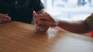 Ahşap kafe masasında el ele tutuşan eşcinsel çift. Tanımlanamayan homoseksüel iki adam romantik bir karşılaşmada şefkat gösteren kollarına dokunuyor. Genç eşcinsel partnerler kafeteryada vakit geçiriyor..