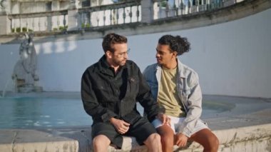 Rahatla lgbtq partnerleri kenarda oturmuş flört ediyorlar. Çok ırklı homoseksüeller güneşli hafta sonlarında dışarıda dinleniyorlar. Mutlu, sevimli eşcinsel çift eski şehir mimarisinin tadını çıkarıyor.