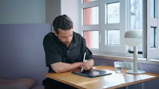 小さなテーブルのクローズアップでタブレットを書くカフェマネージャー 居心地の良いインテリアで作業するパッドコンピュータで働くハンサムなスペイン人男性 無線インターネットを搭載したデジタルガジェットを使用したひげ付きフリーランサーの学生 — ストック動画