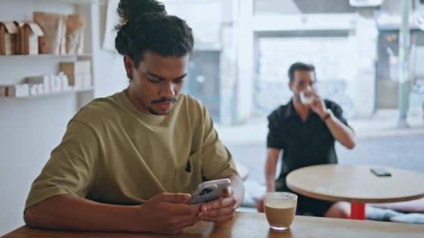 Hombre Latinoamericano Desplazándose Teléfono Inteligente Sentado Cafetería Moderna Con Taza — Vídeo de stock