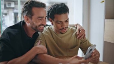 Aynı cinsiyetten çift akıllı telefon başvurusu yapıyor. Küçük kafede alışveriş malzemeleri seçiyorlar. Tasasız eşcinseller cep telefonuyla internet haberlerini tartışıyor. Barda sosyal medyayı izleyen sevimli erkek arkadaşlar..
