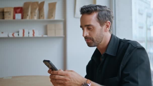 Sonriente Hombre Leyendo Sms Teléfono Inteligente Sentado Acogedor Interior Cafetería — Vídeo de stock