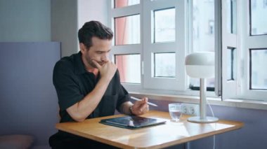 Odaklanmış iş adamı görünümlü tablet ekranlı masa örtüsü kafeteryasını kapatın. Kafedeki ped bilgisayarında çalışan ciddi sakallı bir serbest çalışan. İçeriden bilgi okuyan düşünceli yakışıklı bir adam..