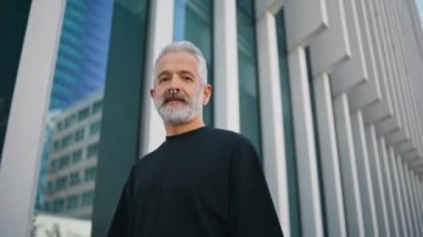 Şehir merkezindeki son sınıf yürüyüş caddesinde sakallı bir ihtiyar. Gri yetişkin görünümlü kamera şehir binasını tek başına geçiyor. Burnuna piercing takan yakışıklı bir adam. Yaşlı erkek, sabah gezintisinin tadını çıkarıyor..