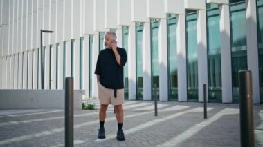 Şehir caddesinde akıllı telefondan konuşan yaşlı bir adam. Odaklanmış gri saçlı erkek şehir merkezindeki iş anlaşmasını tartışıyor. Yetişkin bir iş adamı dışarıda cep telefonuyla konuşur.