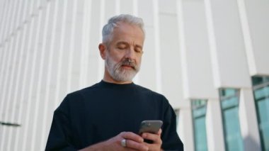 Sokakta son sınıf mesajlaşması. Şehir merkezindeki banka hesaplarını kontrol eden olgun bir iş adamı. Açık havada akıllı telefon kullanarak piercing takan başarılı gri saçlı bir erkek..