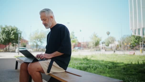 Stilvoller Senioren Schreibcomputer Stadtpark Nachdenklicher Mann Der Freien Mit Kopfhörern — Stockvideo