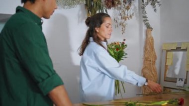 Çiçekçiden esinlenerek dükkanda beste çiçekleri yapılır. Genç adam hafif yaz butik mağazasında gül alışverişi yapıyor. Çiçek işçisi, çiçekçide çalışan kahverengi tenli müşterilere yardım ediyor. Çalışma konsepti.