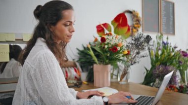 Çiçekçide dizüstü bilgisayarda çalışan ciddi bir çiçekçi. Santraldeki bilgisayarı kullanarak internete odaklanmış kadınları araştır. Güzel iş kızı bilgisi. Başarı teknolojisi kavramı.