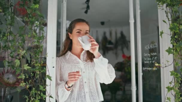 小さなビジネスフラワーストアでリラックスした女性がコーヒーを飲む 地元の植物店で夢見ることを考える集中したビジネスレディを閉じます 成功した労働者がオープンブティックの仕事を開始します フローリストのルーチンコンセプト — ストック動画