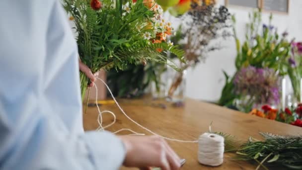 クローズアップ花屋の手は プロの植物店で花の構成を作ります 未知の女性は地元のビジネスでの販売の配達で花を結びます 自然な装飾の概念 — ストック動画