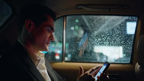 紧张经理在商务车特写中使用智能手机 有压力的男人在豪华汽车里拿手机是犯了个工作错误 在黑暗的汽车沙龙里看着雨滴窗口的导演生气了 — 图库视频影像