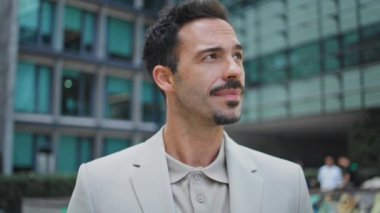 Gülümseyen CEO şehir merkezinde poz veriyor. Genç esmer adam cam mimarinin arka planında kameraya bakıyor. Yakın plan. Gevşemiş İspanyol adam uzaktan bakıyor. Sokakta tek başına zum yapıyor.