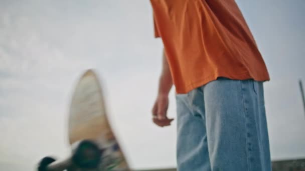 纹身滑板手在城市特写处玩滑板 年轻的滑板运动员站在多云的天空背景与滑板 默默无闻的职业男子独自在长板上摆出夏日街的姿势 — 图库视频影像