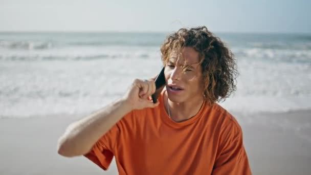 Poważny Kręcony Facet Rozmawiający Smartfonem Słonecznej Plaży Przystojny Zmartwiony Facet — Wideo stockowe