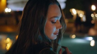 Fıskiye gecesinin yakınında romantik bir kız duruyor. Kasaba mimarisinde yalnız poz veren rahat çekici bir kadın. Muhteşem genç modelin portresi Alacakaranlıkta kentsel güzelliğin tadını çıkar