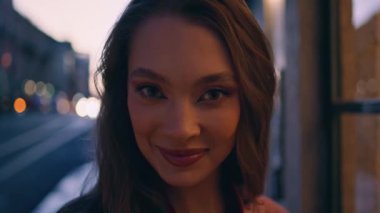 Karanlık şehir caddesinde poz veren muhteşem bir model. Kameraya kaygısız bakıyor. Güzel, gülümseyen bir hippi kadının portresi gecenin geç saatlerinde şehir caddesinde tek başına dikiliyor. Mutlu kız turist gecenin tadını çıkarıyor.