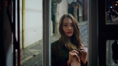 Şehvetli kadın, akşam caddesinde cam binanın yanında duruyor. Kapıları kapatın. Karanlık şehir kamerasında poz veren güzel moda bir model. Güzel, uzun saçlı kız gece kasabada dinleniyor..