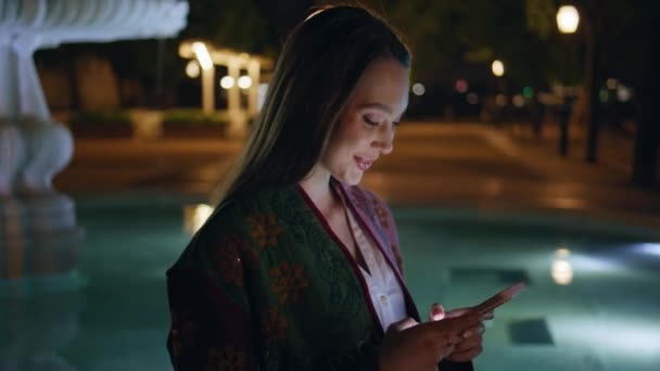 Mulher Sorridente Olhando Tela Smartphone Fonte Cidade Tarde Noite Fechar — Vídeo de Stock
