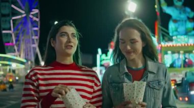 Hafta sonları kızlar lunaparkta yürür. Aydınlanmış atlıkarıncada elinde patlamış mısırla konuşan gülen en iyi arkadaşlar. Tasasız gençler gece eğlence parkı festivalinde takılıyor..